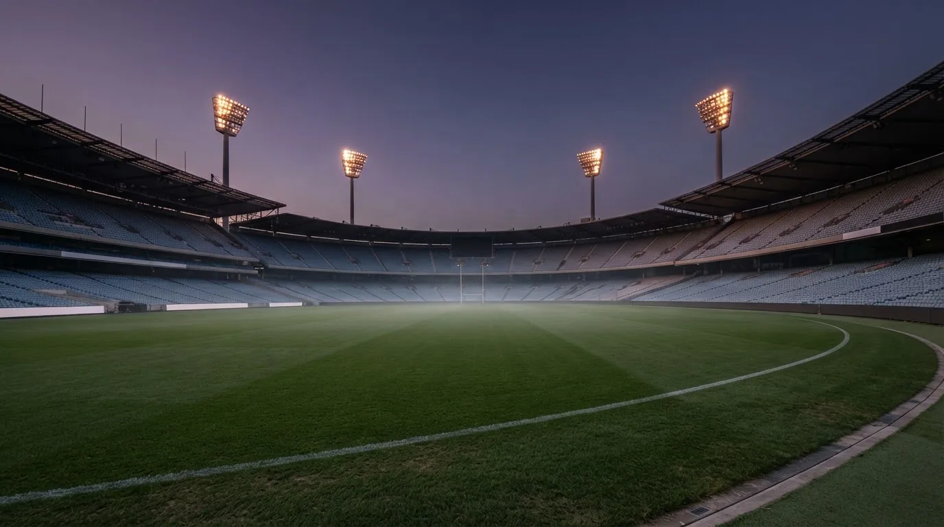 An empty football stadium with floodlight masts at dusk