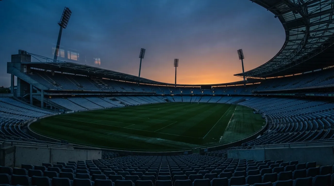 An empty football stadium with floodlight masts at dusk
