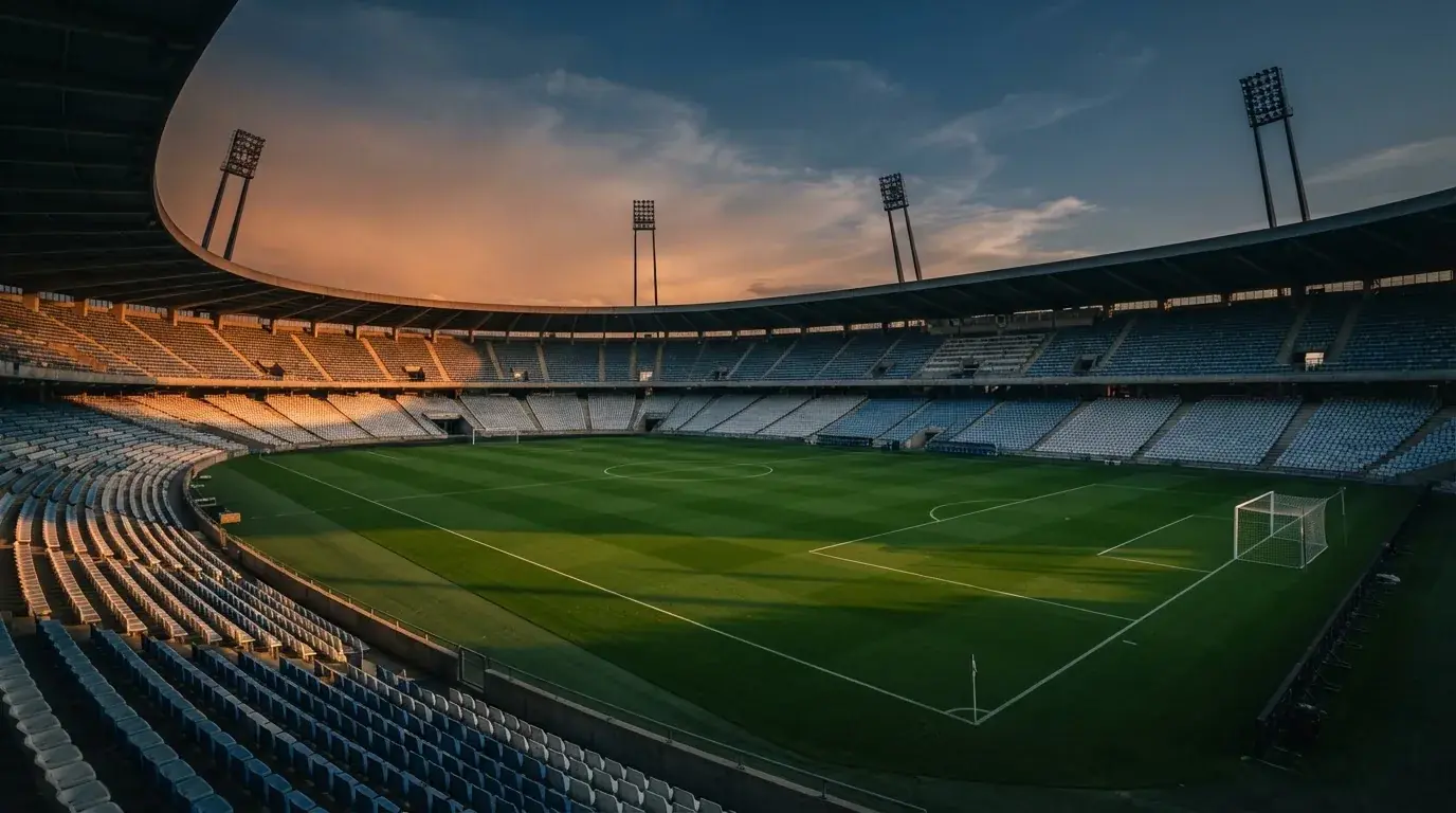 An empty football stadium with floodlight masts at dusk