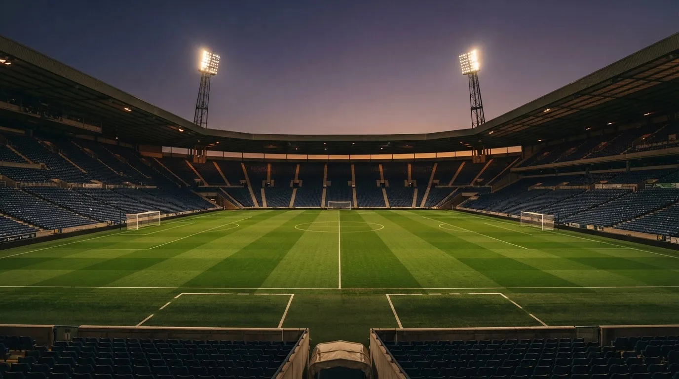 An empty football stadium with floodlight masts at dusk