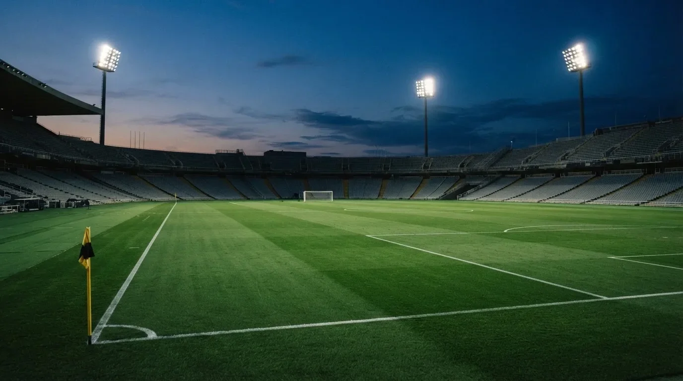 An empty football stadium with floodlight masts at dusk