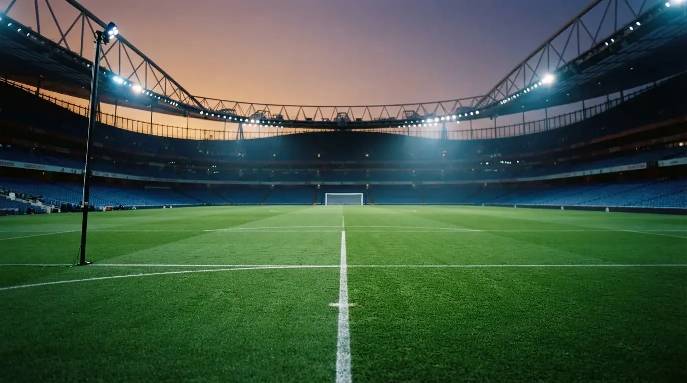 An empty football stadium with floodlight masts at dusk