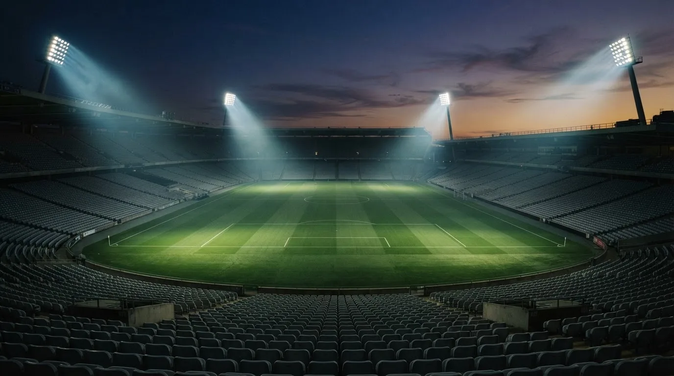 An empty football stadium with floodlight masts at dusk