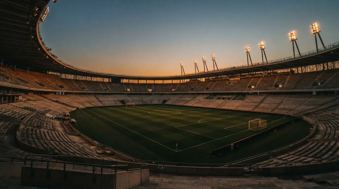 An empty football stadium with floodlight masts at dusk