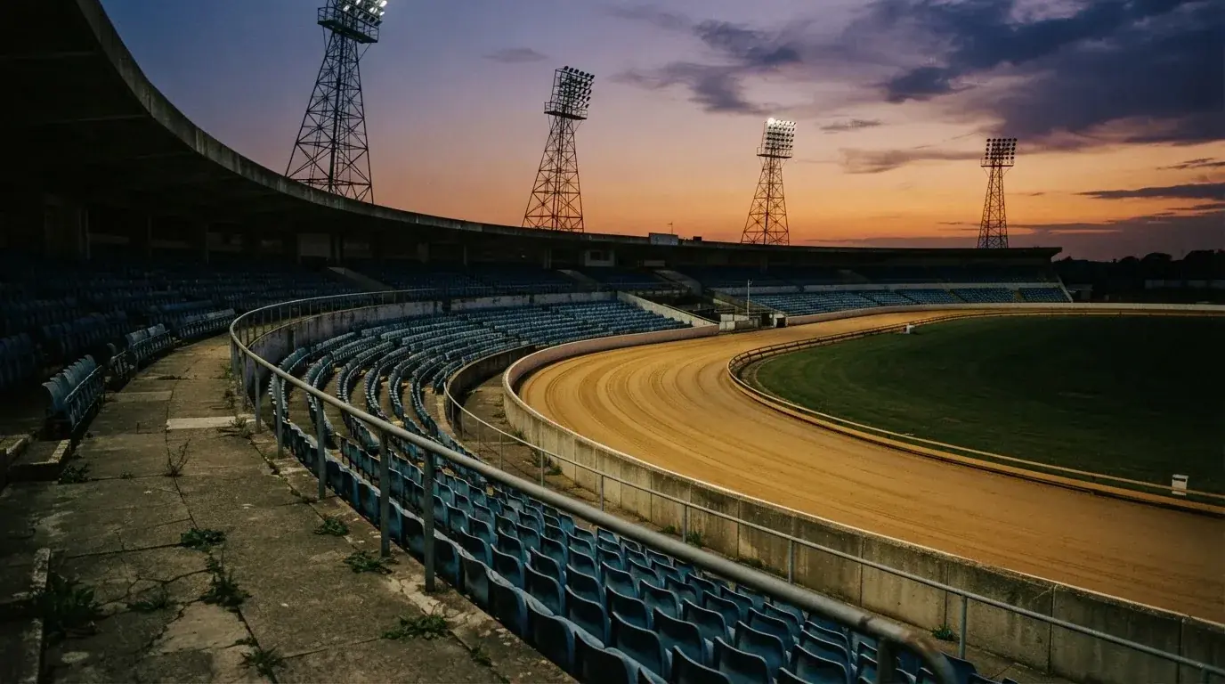 An empty football stadium with floodlight masts at dusk