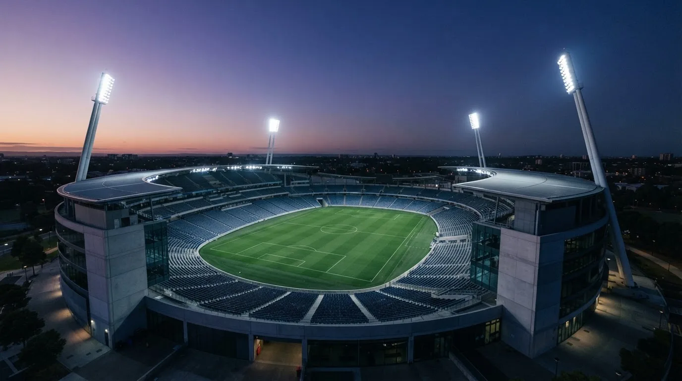 An empty football stadium with floodlight masts at dusk