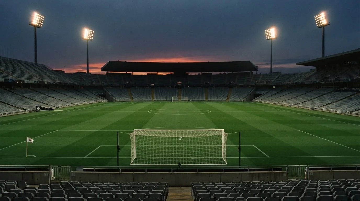 An empty football stadium with floodlight masts at dusk