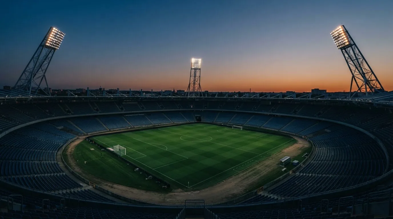 An empty football stadium with floodlight masts at dusk