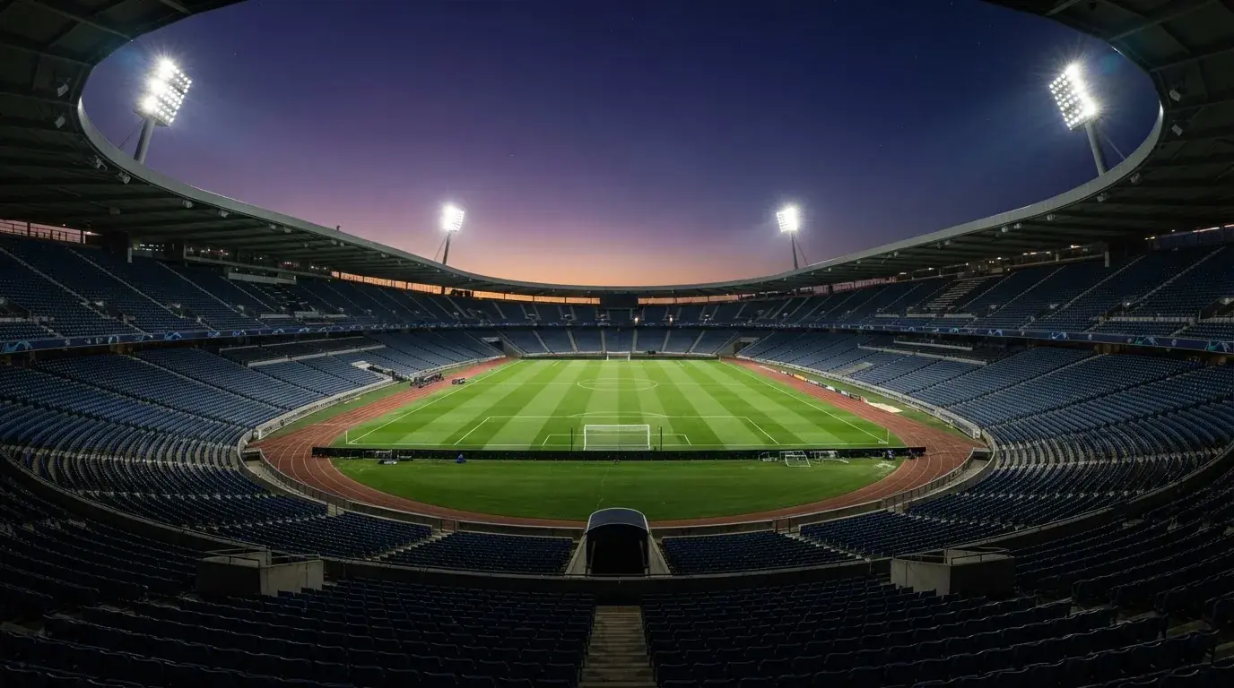 An empty football stadium with floodlight masts at dusk