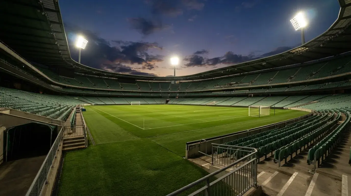 An empty football stadium with floodlight masts at dusk