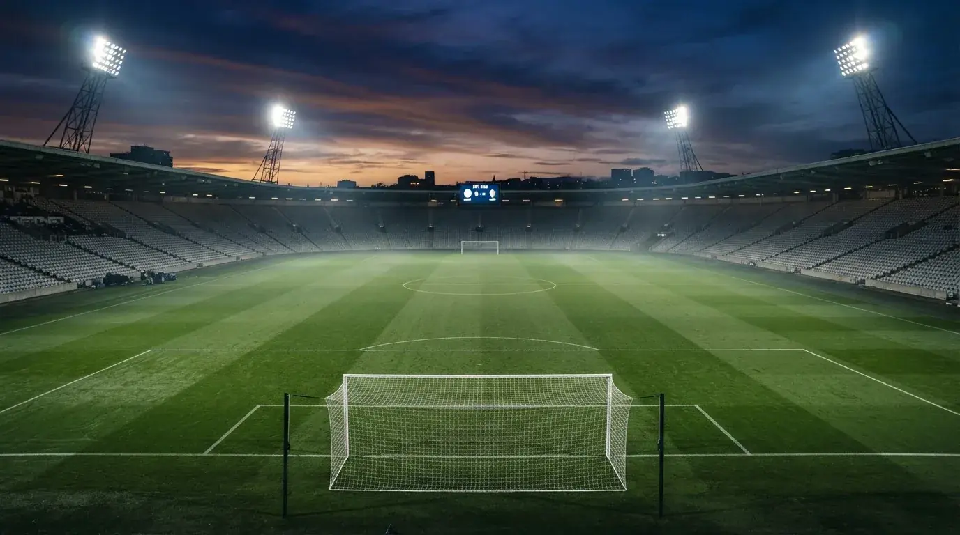 An empty football stadium with floodlight masts at dusk
